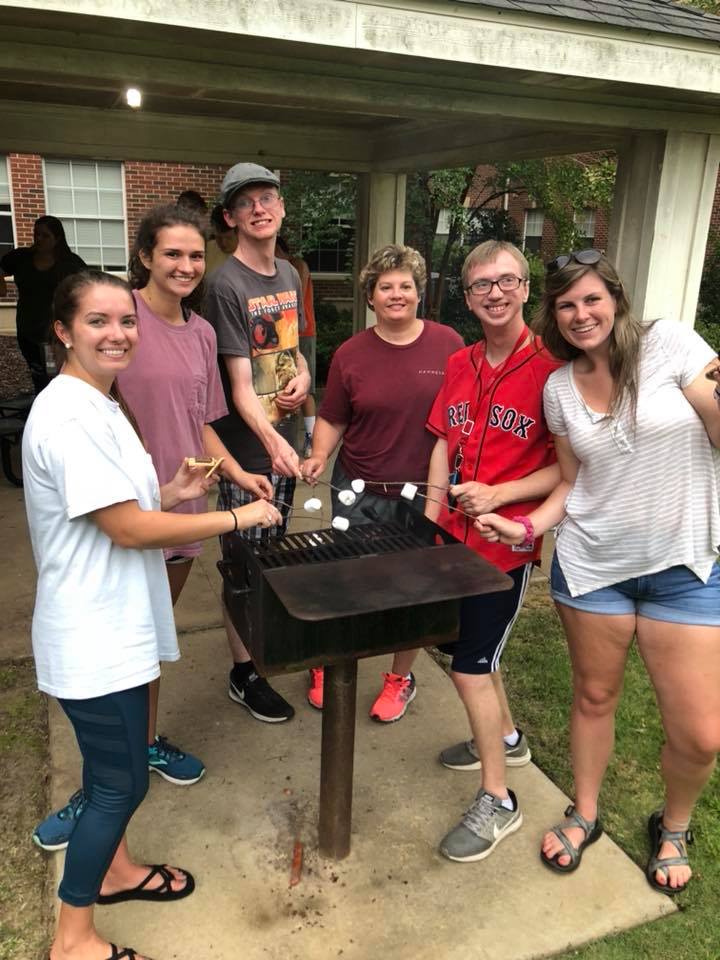 Group toasting marshmallows over a grill