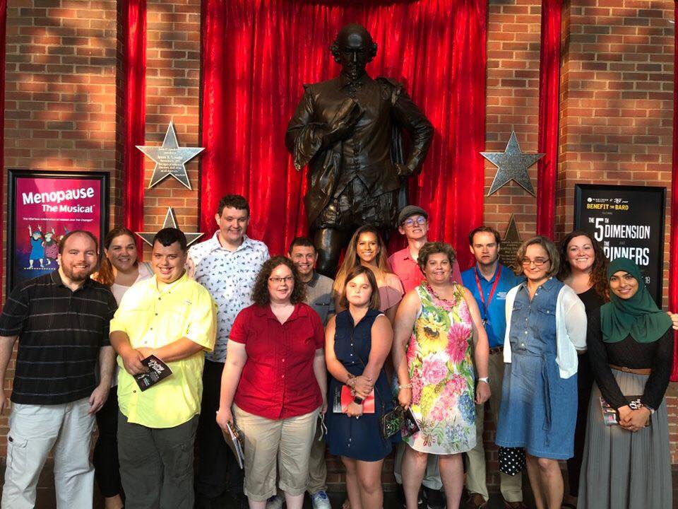 Group of people standing in front of theater statue