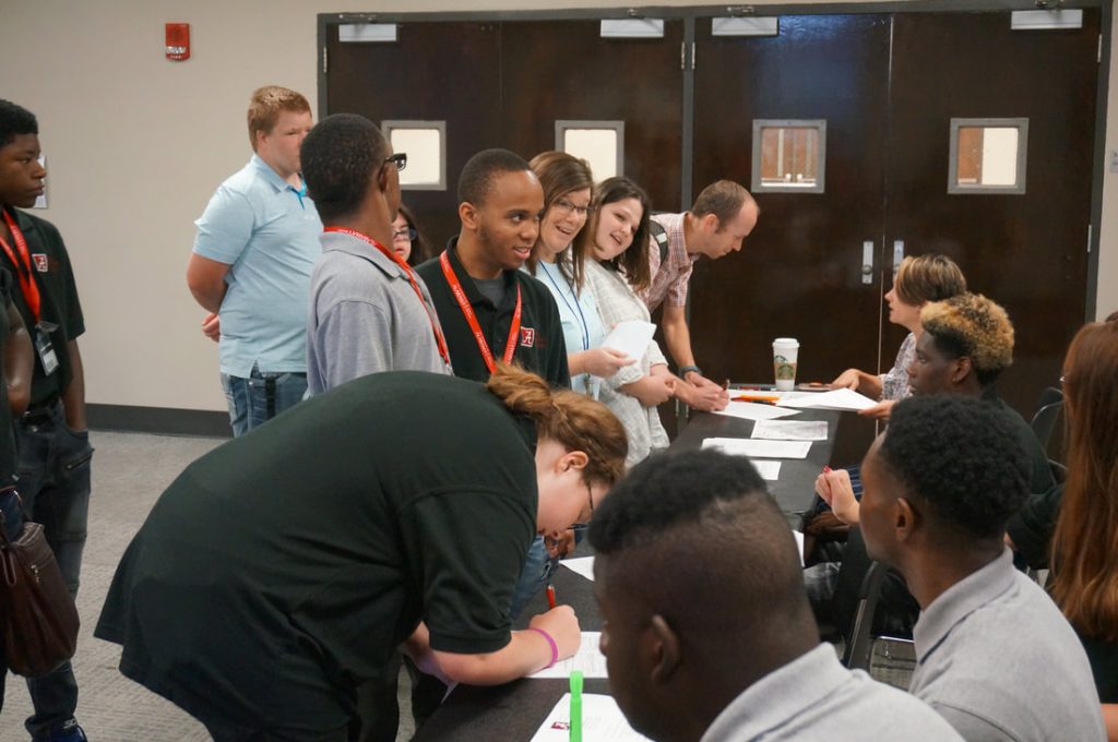 People talking and writing at a booth