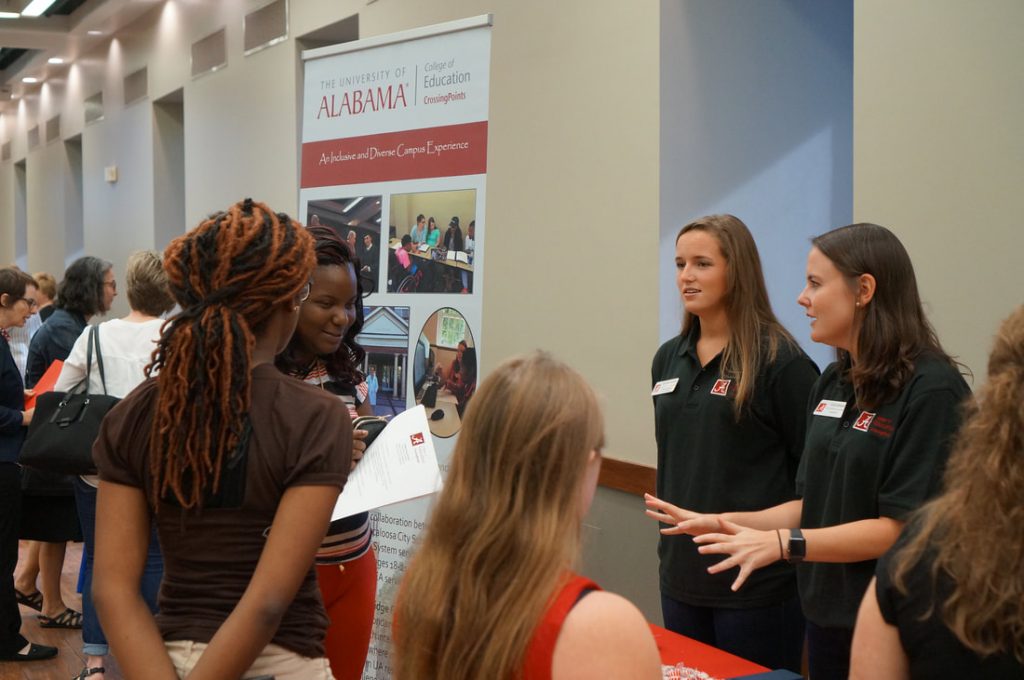 People talking around University of Alabama booth