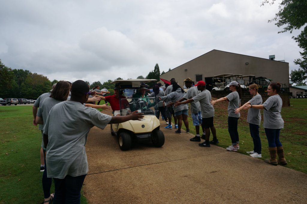 People high fiveing passing golf cart