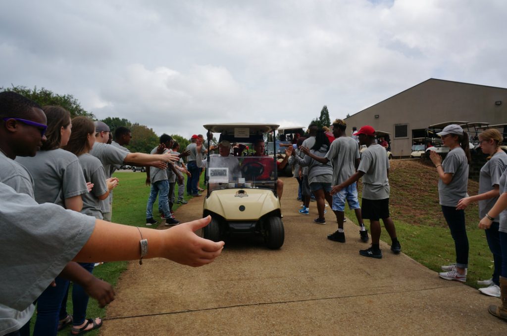 People high fiveing passing golf cart